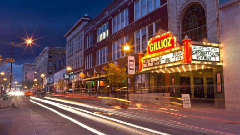 Nighttime view of the historic Gillioz Theatre marquee illuminated in downtown Springfield, Missouri, with city lights and traffic trails creating a vibrant urban atmosphere.